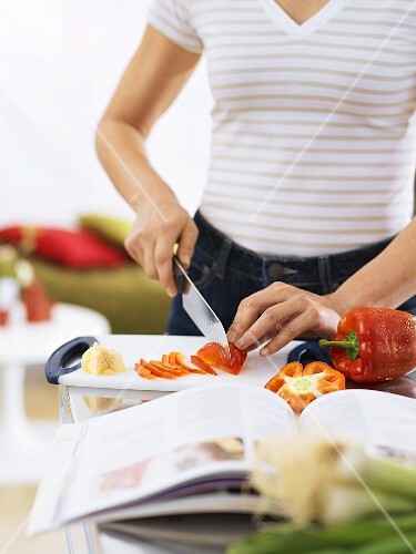 Woman slicing red pepper in kitchen