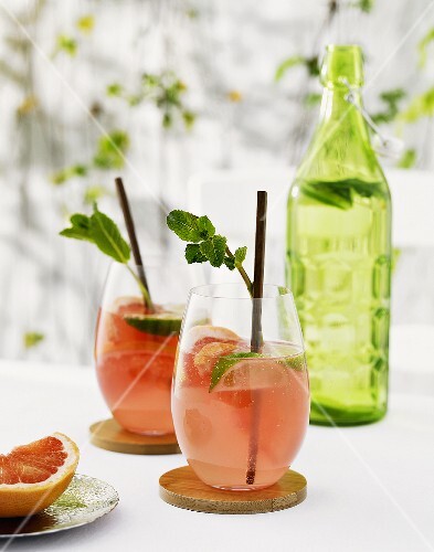 Pink grapefruit drinks with lime wedges and mint