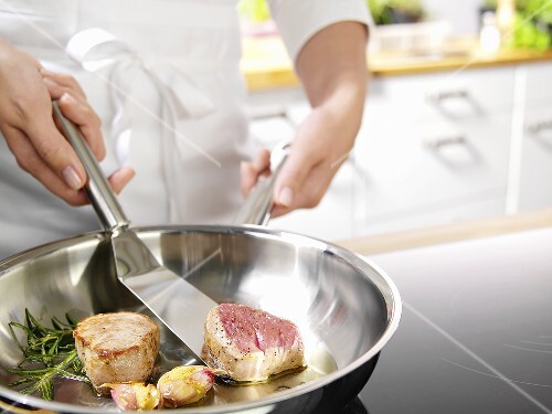 Koch brät Schweinefilets in Butterschmalz an