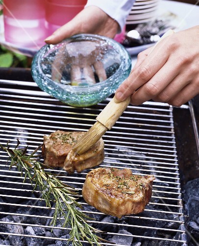 Brushing lamb chops on barbecue with oil