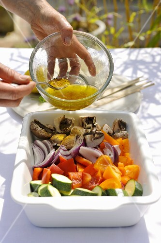 Vegetables for vegetable kebabs being drizzled with a marinade