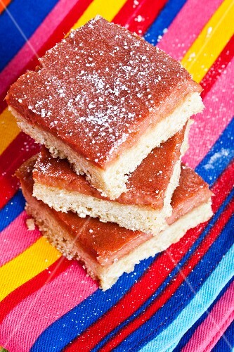 Rhubarb bars, stacked, on a striped cloth