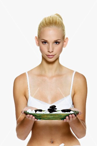 Woman holding dish of massage stones