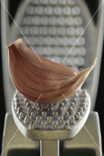 A garlic clove in a garlic press (close-up)