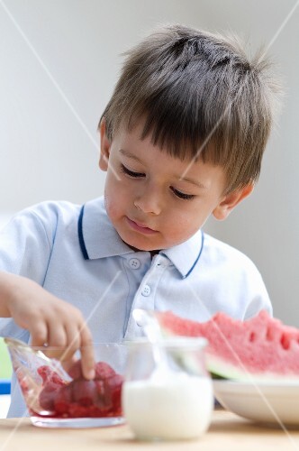 A little boy eating raspberries