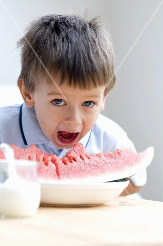 Small boy biting into a slice of watermelon