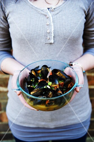 A woman holding a bowl of mussels