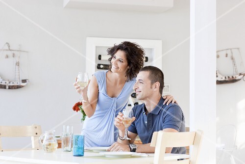 A woman and a man drinking wine at a kitchen table