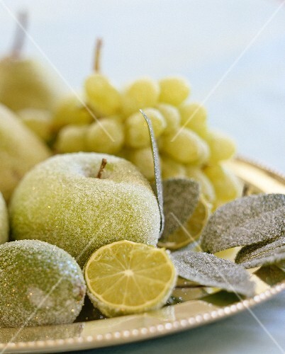 Decorative frosted fruit presented on a silver tray glisten in the candlelight