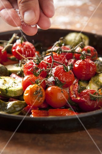 Roasted cherry tomatoes being sprinkled with fleur de sel