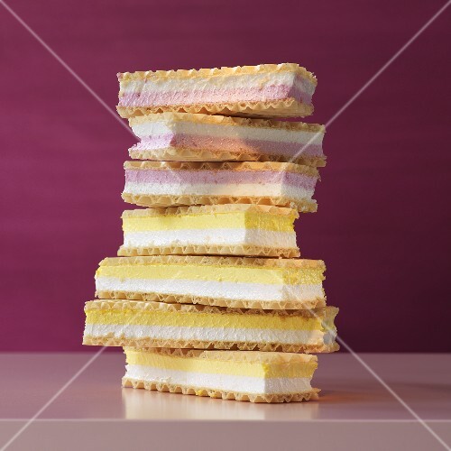 A stack of cream-filled wafers in front of a rose colored background