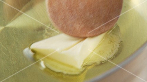 Olive oil being heated with piece of butter