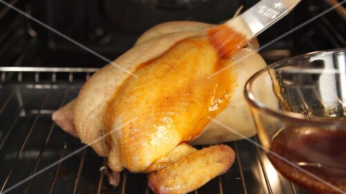 Roast chicken being brushed with spiced butter
