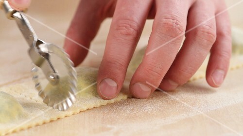 Ravioli being cut out with a dough wheel