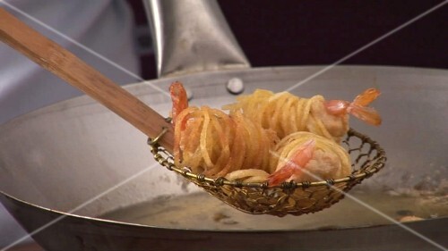 Taking deep-fried noodle-wrapped prawns out of wok