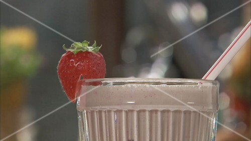 Making strawberry shake and pouring it into a glass