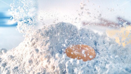 Egg yolk falling into a heap of flour