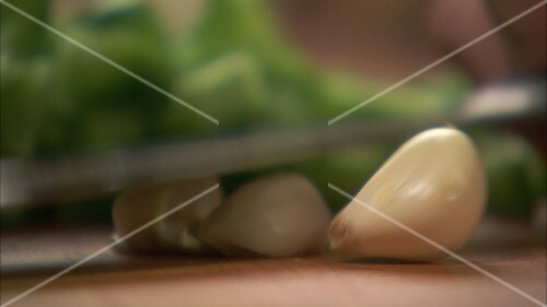 Crushing cloves of garlic with a knife and chopping them