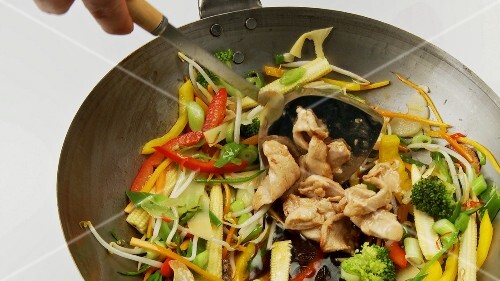 Cooking vegetables in wok and adding chicken fillet