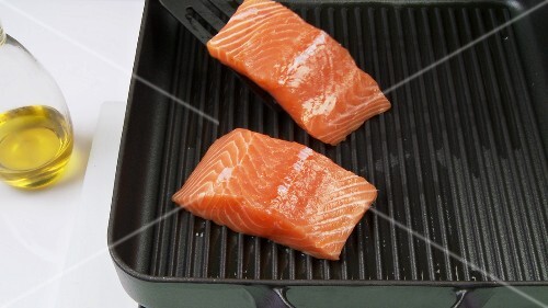 Cutting salmon fillet into pieces and frying it in a grill frying pan