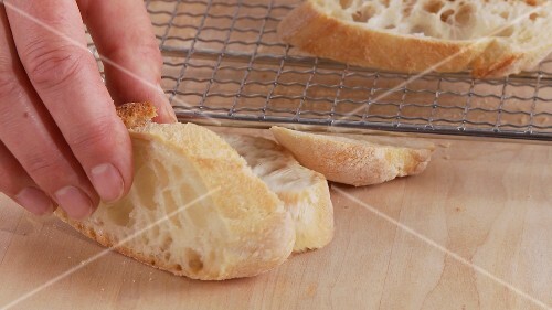 Ciabatta slices being placed on an oven rack