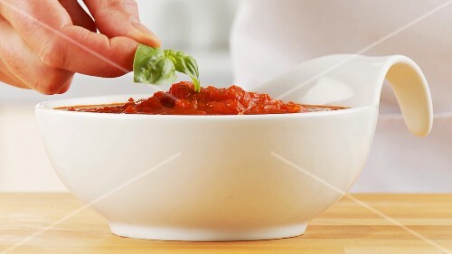 Garnishing tomato sauce with basil