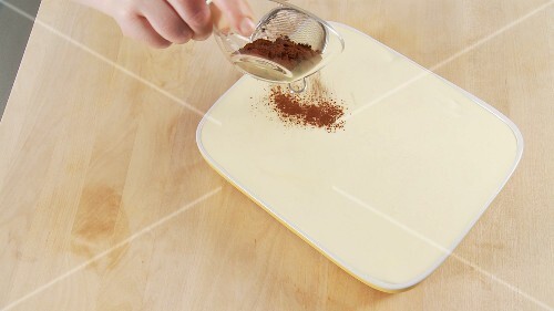 Tiramisu being dusted with cocoa powder