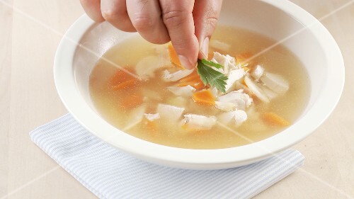 Broth being poured over small pieces of vegetables and chicken breast