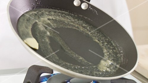 Butter being melted in a pan and pancake dough being poured in