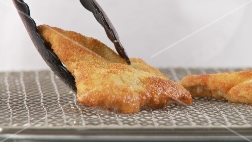 Escalop á la viennoise being removed from the pan and dried