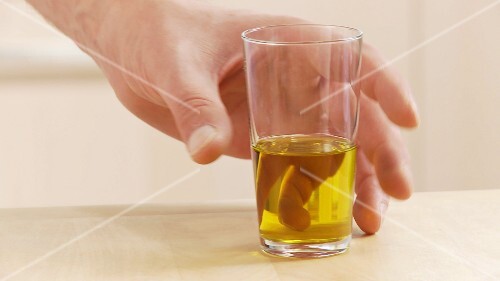 A glass of olive oil being taken off the work surface