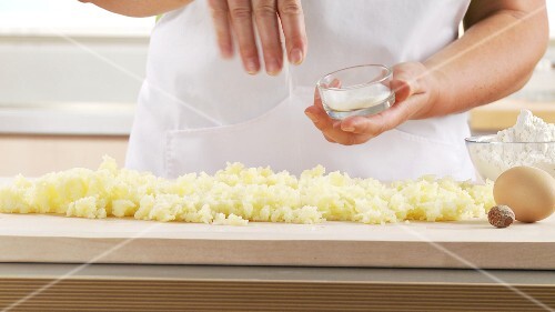 Cooked potatoes being seasoned with salt