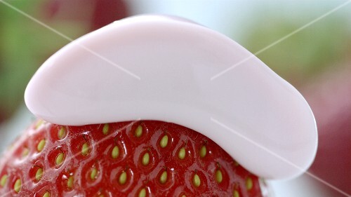 A strawberry with a dollop of whipped cream (close-up)