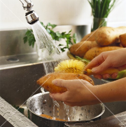 Hands Washing Sweet Potatoes in a Sink
