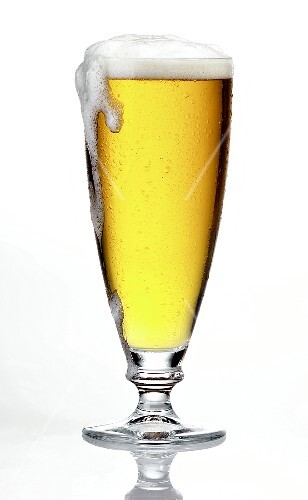 Glass of light beer, frothing over