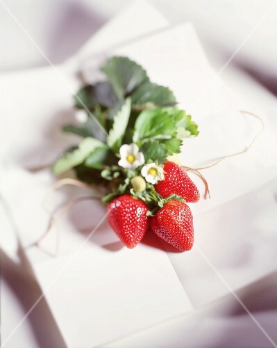 A bunch of three strawberries with flowers and leaves