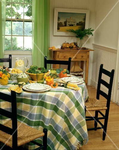 Country house table set in summery style with salad, corn