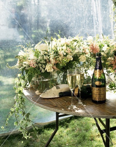 Champagne bottles, glasses and flower on table in garden