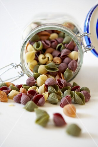 Organic Multi-Colored Shell Pasta Spilling From a Canister