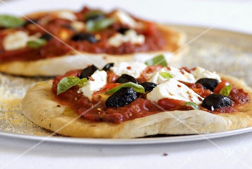 Pizza mit Tomaten, Mozzarella, Oliven & Basilikum