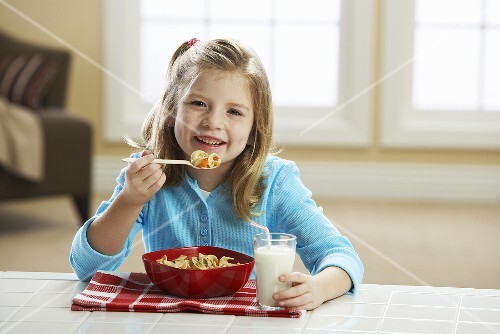 Little Girl Eating a Bowl of Pasta for Lunch; With Milk