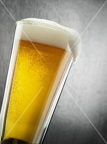 Glass of Light Beer with Foam Spilling Over