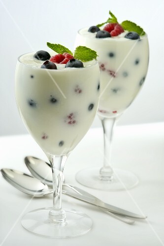 Yogurt with Raspberries and Blueberries in Two Stem Glasses;Mint Garnish