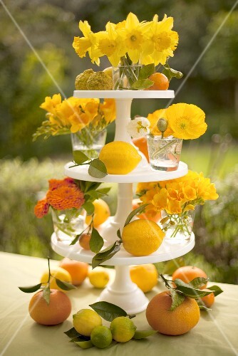 Dreistufige Etagere mit orangefarbenen Blumen und Zitrusfrüchten