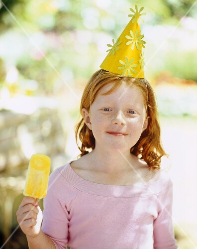 A young girl at a summer birthday party enjoying an ice lolly