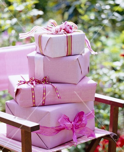 Geschenkkartons in rosa Papier gewickelt auf einem Stuhl im Garten