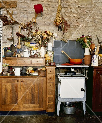 Old-fashioned oven in country kitchen with wooden cupboards and stone walls