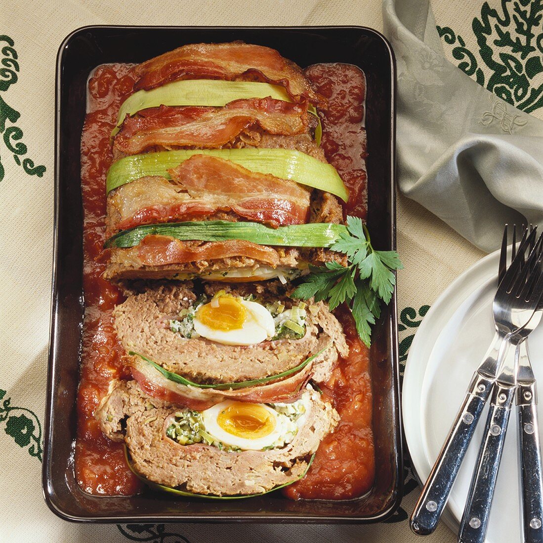 Spicy meatloaf with boiled eggs on tomato sauce