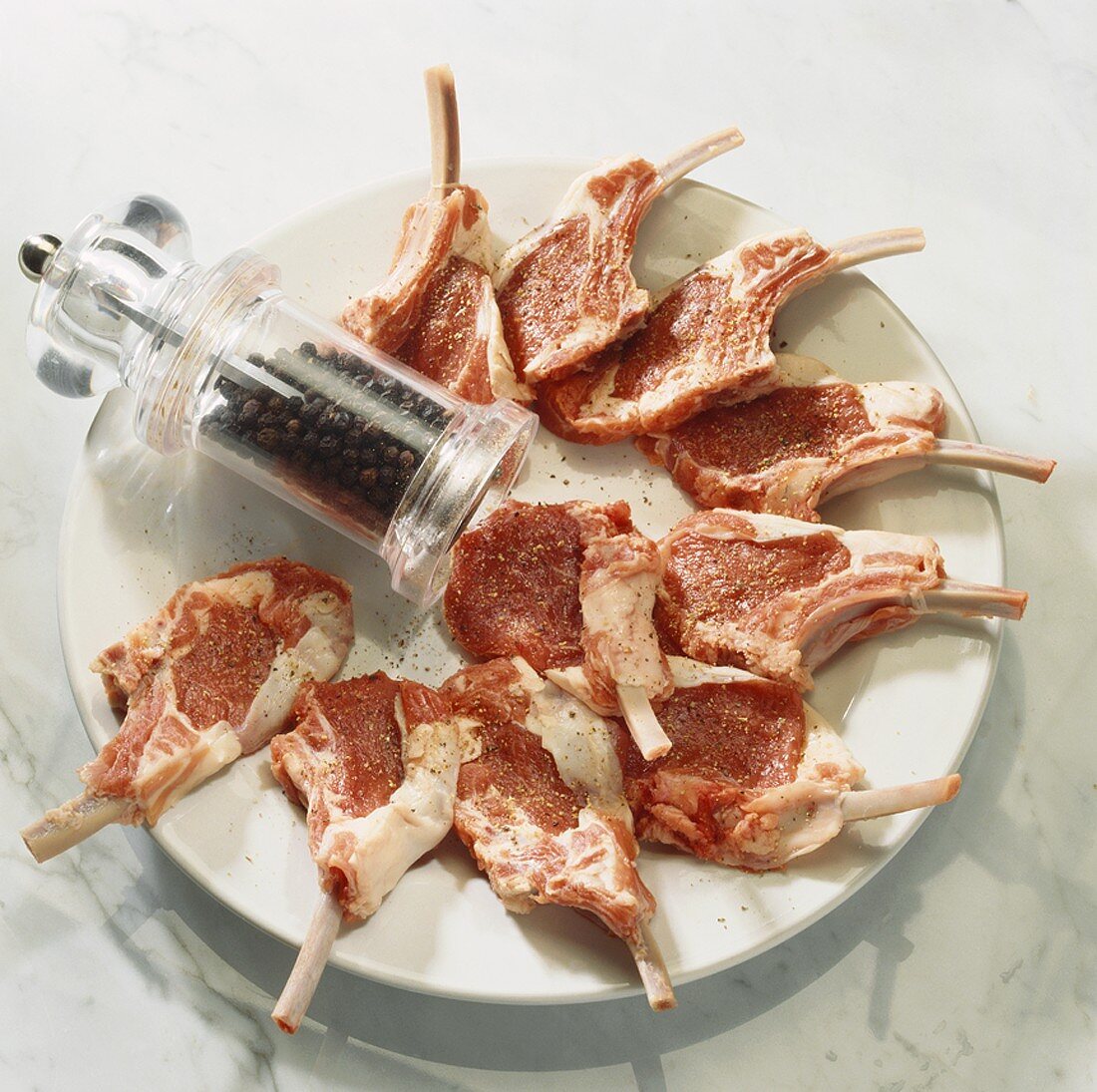 Raw lamb chops and a pepper mill