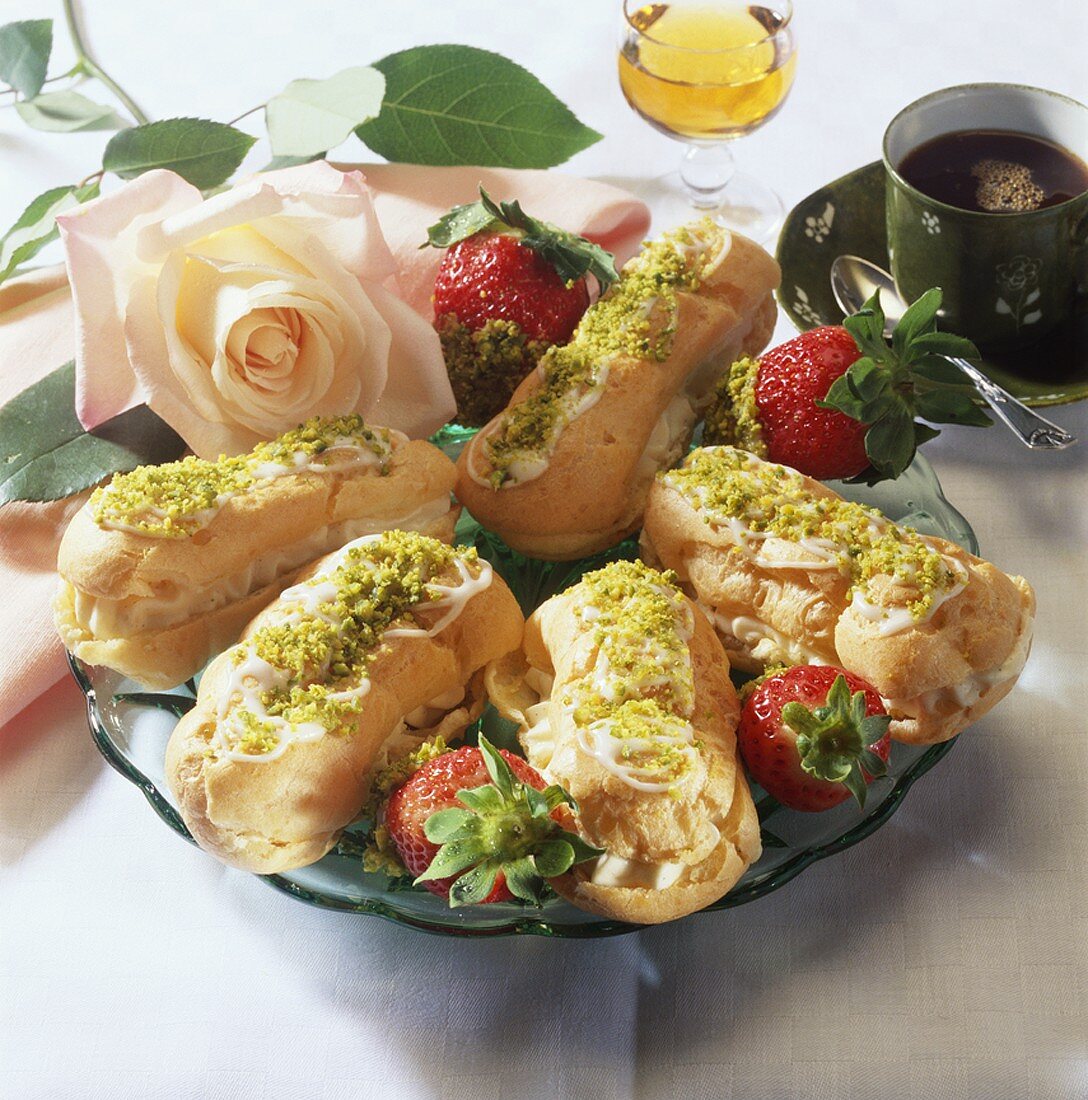 Filled éclairs and strawberries with ground pistachios